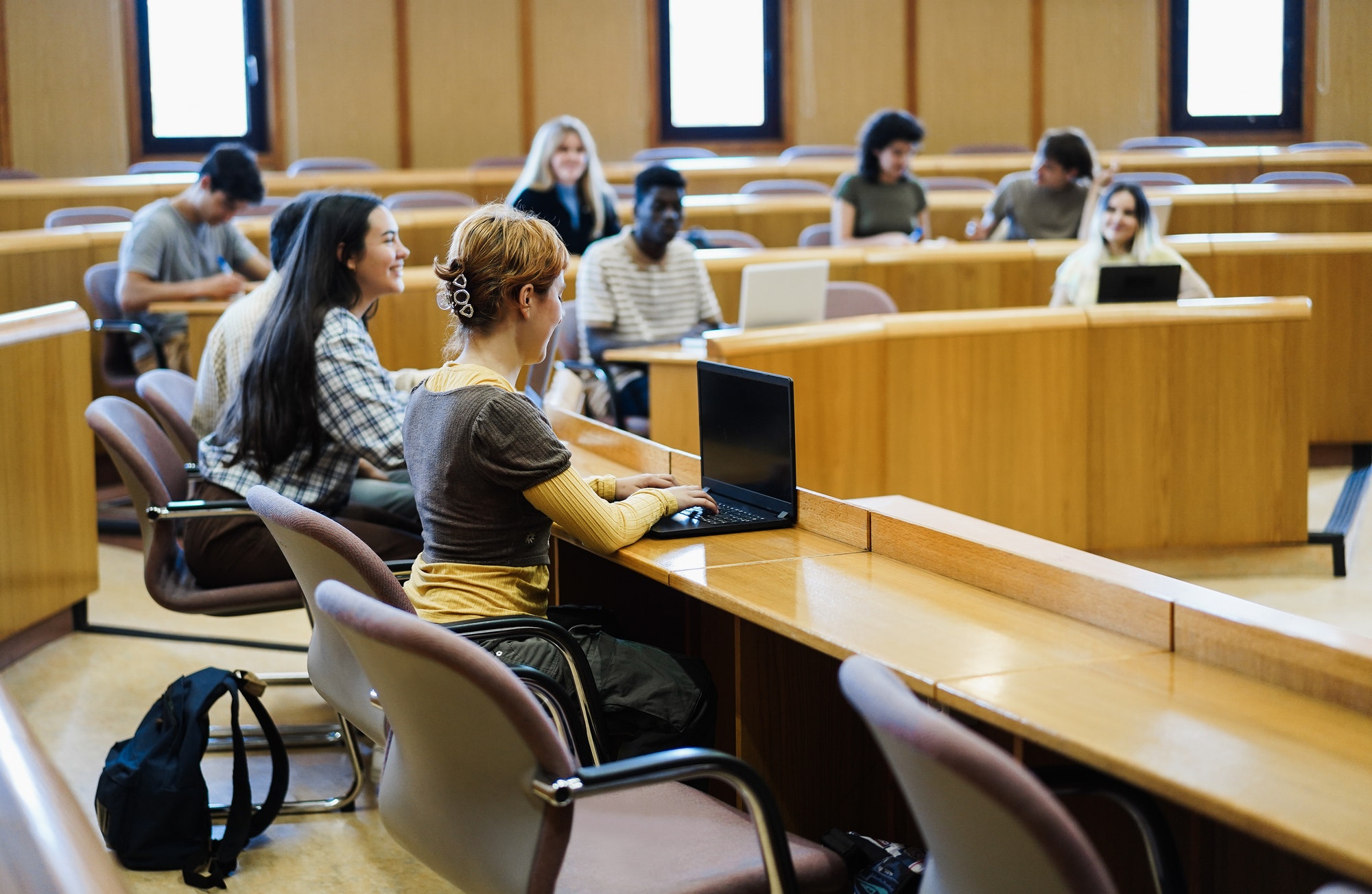 Young students working with laptop computers inside classroom at school university